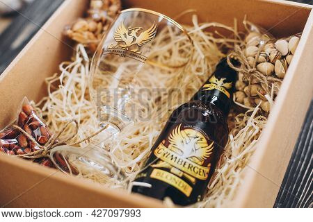 Lviv, Ukraine - December 1, 2017: Grimbergen Beer Bottle, Glass Cup And Salted Nuts Snacks On Straw 