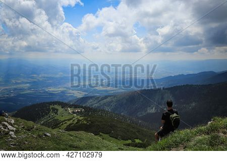 Athlete In A Black T-shirt Sits On Top Of Mala Fatra Mountain. Hiker Walks Along Ridges Of Lesser Fa