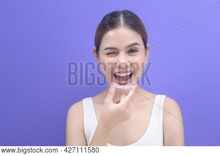 Young Smiling Woman Holding Invisalign Braces In Studio, Dental Healthcare And Orthodontic Concept..