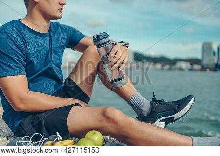 Sport Man Sitting After Running And Holding Water Bottle Drink. Sport Thirsty And Resting After Exer