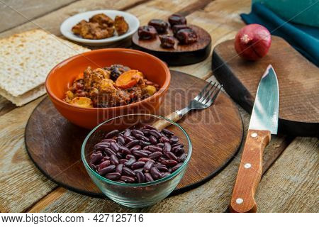 Jewish Dish Chelnt With Meat In A Plate On A Wooden Table On A Stand Next To A Knife And Ingredients
