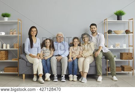Portrait Of Happy Multi-generational Family Sitting All Together On Sofa At Home
