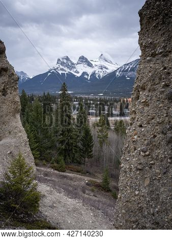 Three Sisters Mountain Above Canmore Framed By Hoodoos, Shot At Canmore, Alberta, Canada