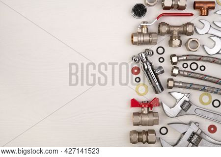 Plumber tools and spare parts on white wooden background, top view, flat lay with copy space