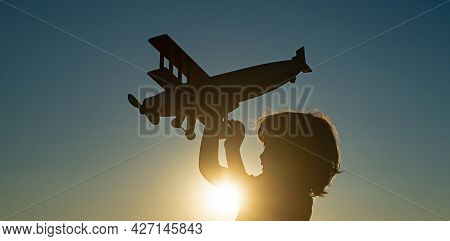 Child Pilot Aviator With Airplane Dreams Of Traveling. Child Dreams. Child On The Background Of Suns