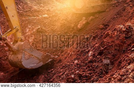 Metal Bucket Of Backhoe Digging Soil. Backhoe Working By Digging Soil At The Construction Site. Exca