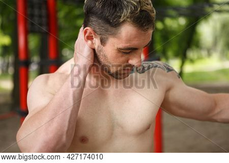 Close Up Of A Muscular Shirtless Man Rubbing Achine Neck After Exercising