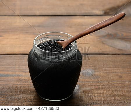 Fresh Black Paddlefish Caviar In A Wooden Brown Spoon And A Full Can Of Caviar On A Wooden Table, De