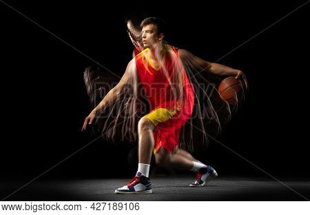 One Young Basketball Player Training With Ball Isolated On Dark Background With Stroboscope Effect. 