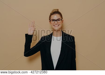 Positive Young Caucasian Woman In Classic Wear Isolated On Beige Background Showing Ok Sign Or Okay 