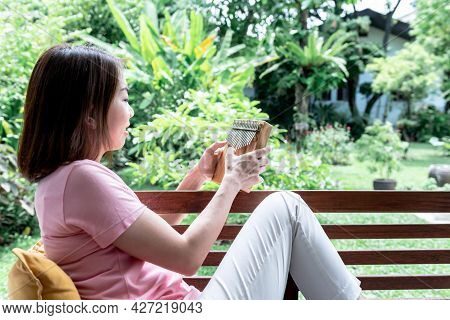 Asian Attractive Woman Sitting And Relax With Playing Kalimba, Which Is A Small Musical Instrument, 