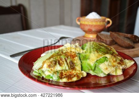 Fried Fresh Green Cabbage On The Red Ceramic Plate, Selective Focus Onb The Blurred Kitchen Backgrou