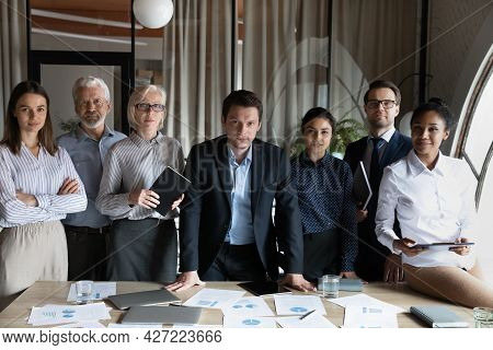 Confident Diverse Employees Of Different Age Standing At Meeting Table