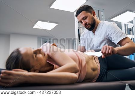 Woman Lying On Treatment Bed Physiotherapist Presses Her Abs With Iastm Instrument Side View