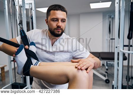 Strength Training Of Young Woman Legs, Knee On Flexible Simulator In Rehabilitation Center Closeup