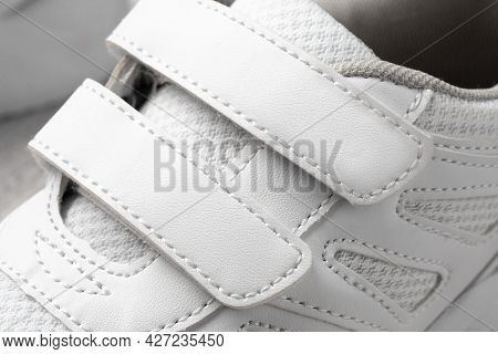 Photo Of White Childrens Sneakers. Macro Photography Of Sports Sneakers Made Of Leather And Fabric W