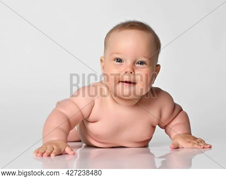 Cute Baby Infant Lies On His Stomach Against A Light Background, He Is Naked In One Diaper, Falls On