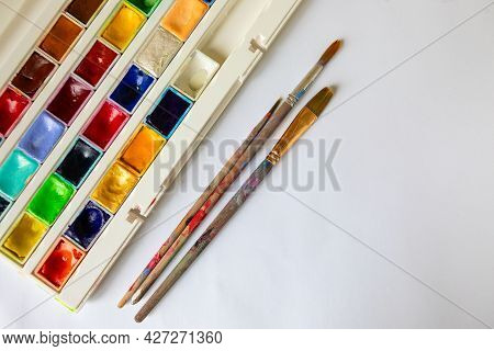 Watercolors In Cuvettes In A Box And Brushes For Painting On A White Sheet Of Paper. Blank For Desig