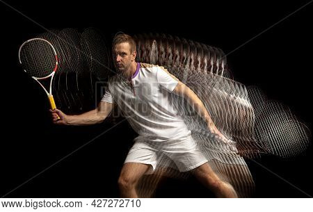 Portrait Of Young Man, Male Tennis Player In Motion And Action Isolated On Dark Background. Strobosc