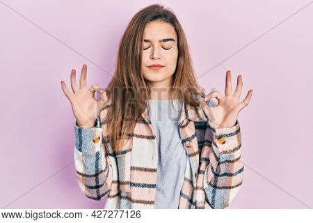 Young caucasian girl wearing casual clothes relaxed and smiling with eyes closed doing meditation gesture with fingers. yoga concept. 