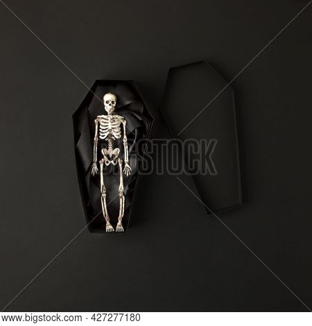 Toy Skeleton Of Man In Papercraft Coffin On Black Background, Stylish Monochrome Halloween Concept, 