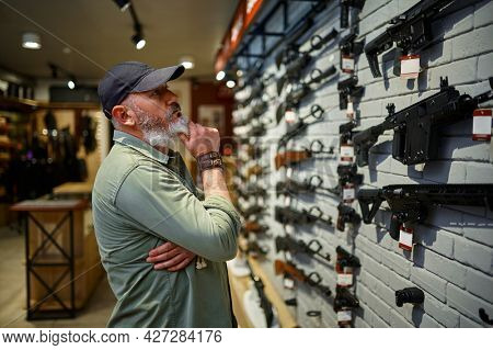 Male seller at showcase with rifles in gun store
