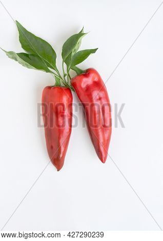Red ''Corno di Toro'' Peppers with Leaves on White Background