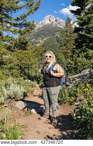 Full Body Portrait Of A Smiling Blonde Female Hiker On The Trail At Grand Teton National Park