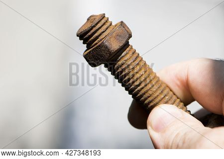 Old Rusty Bolt, Iron Rod With Screw Threads, In Hand. Rusted Mechanical Components. Holding Threaded