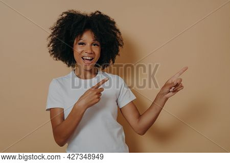 Young African American Girl Wearing Casual Clothes Cheerfully And Broadly Smiling While Pointing Wit