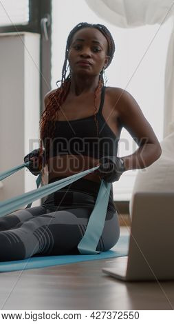 Fit Black Woman In Sportswear Looking At Online Workout On Laptop Working Body Muscle Using Fitness 