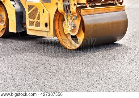 The Metal Cylinder Of The Yellow Road Vibrating Roller Compacts The Fresh Asphalt Powerfully On The 