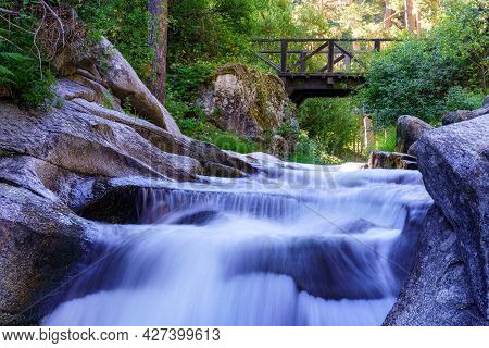 Several Waterfalls Passing Under A Wooden Bridge. Navacerrada.