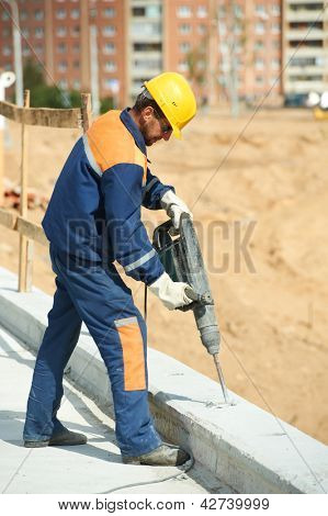 Portarait of positive Builder worker with pneumatic hammer drill equipment at construction site