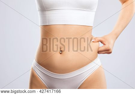 Girl Pulls The Skin On The Abdomen, Showing The Body Fat In The Abdominal Area And Sides. Treatment