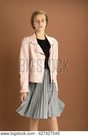 Happy Girl Whirling Against Brown Background. Joyful Attractive Brown Haired Teen Girl Dressed Pink 