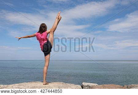 Caucasian Girl Performing Rhythmic Gymnastics Exercises With The Leg Up And The Foot Over The Head B