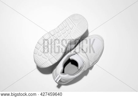 Macro Top View Two White Woman Sneakers, One Sneaker Lies Sole Up With Hard Shadows Isolated On A Wh