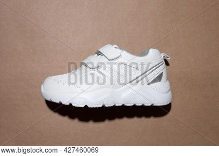 Flat Lay One White Child Sneaker With Velcro Fasteners For Easy Slipping On The Side In The Center I
