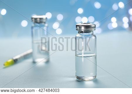 Two Bottles Of Vaccine And Syringe Injection On Blue Background. Concept Of Prevention, Immunization