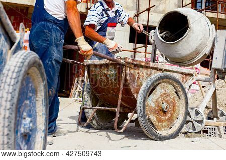 Workers Are Pour Mortar In Wheelbarrow Attached To Crane Hooks To Carry, Transport Up.