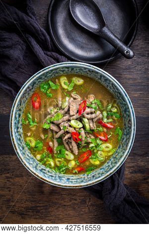 German liver dumpling soup with onion and vegetable on dark background