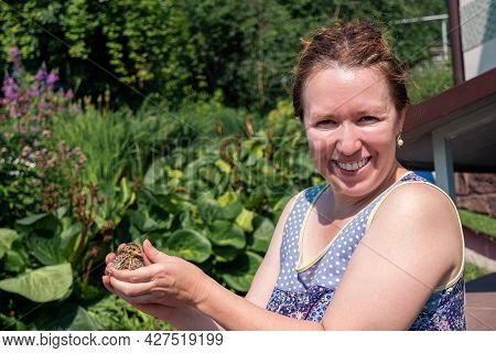 Smiling Woman Farmer Holds Domestic Quail Chicken In Her Hands Outdoor
