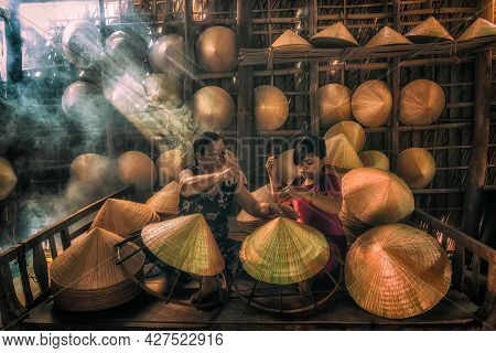 Vietnamese Old Woman Craftsman Teaching The Grandchild Making The Traditional Vietnam Hat In The Old