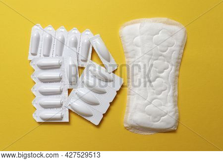 Sanitary Pads And Vaginal Suppositories On A Yellow Background, Top View, Flat Lay. The Concept Of W