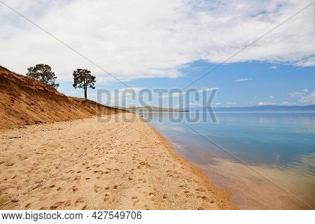 The Shore Of Lake Baikal On A Cloudy Summer Day. Calm Blue Water, Sandy Beach. Beautiful Summer Land