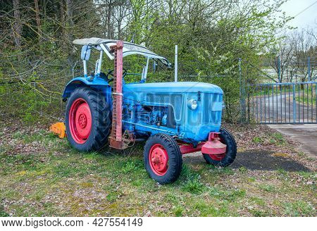 Blue Tractor Old On The Background Of Trees In Spring