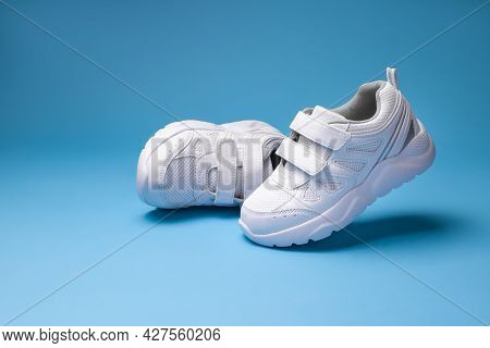 Two White Girl Sneakers , One Sneaker Flying In The Air And The Other Lying On Its Side Isolated On 