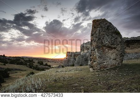 Sunset On The Night Of The Summer Solstice With A Megalithic Menhir In The Foreground And A Rocky Mo