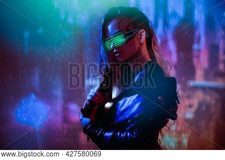 Cyberpunk concept. A courageous cyberpunk girl warrior stands with a gun in her hands against the backdrop of the night city of the future. Game, virtual reality. 